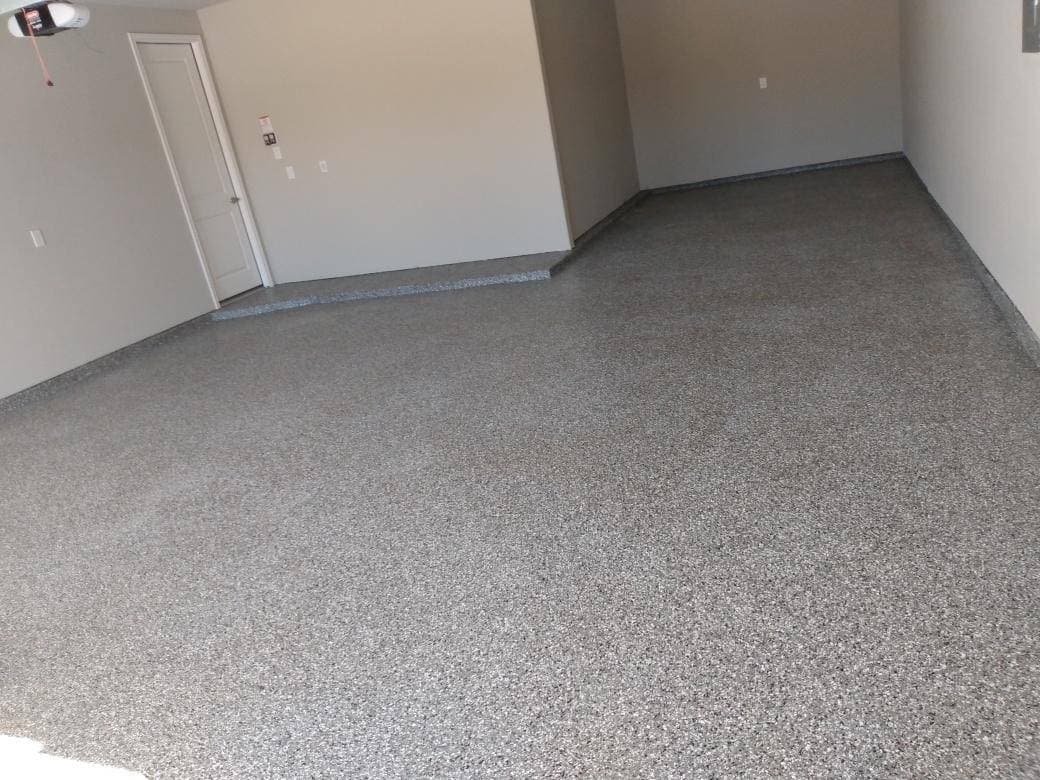 Newly coated gray epoxy garage floor with textured finish and clean walls.
