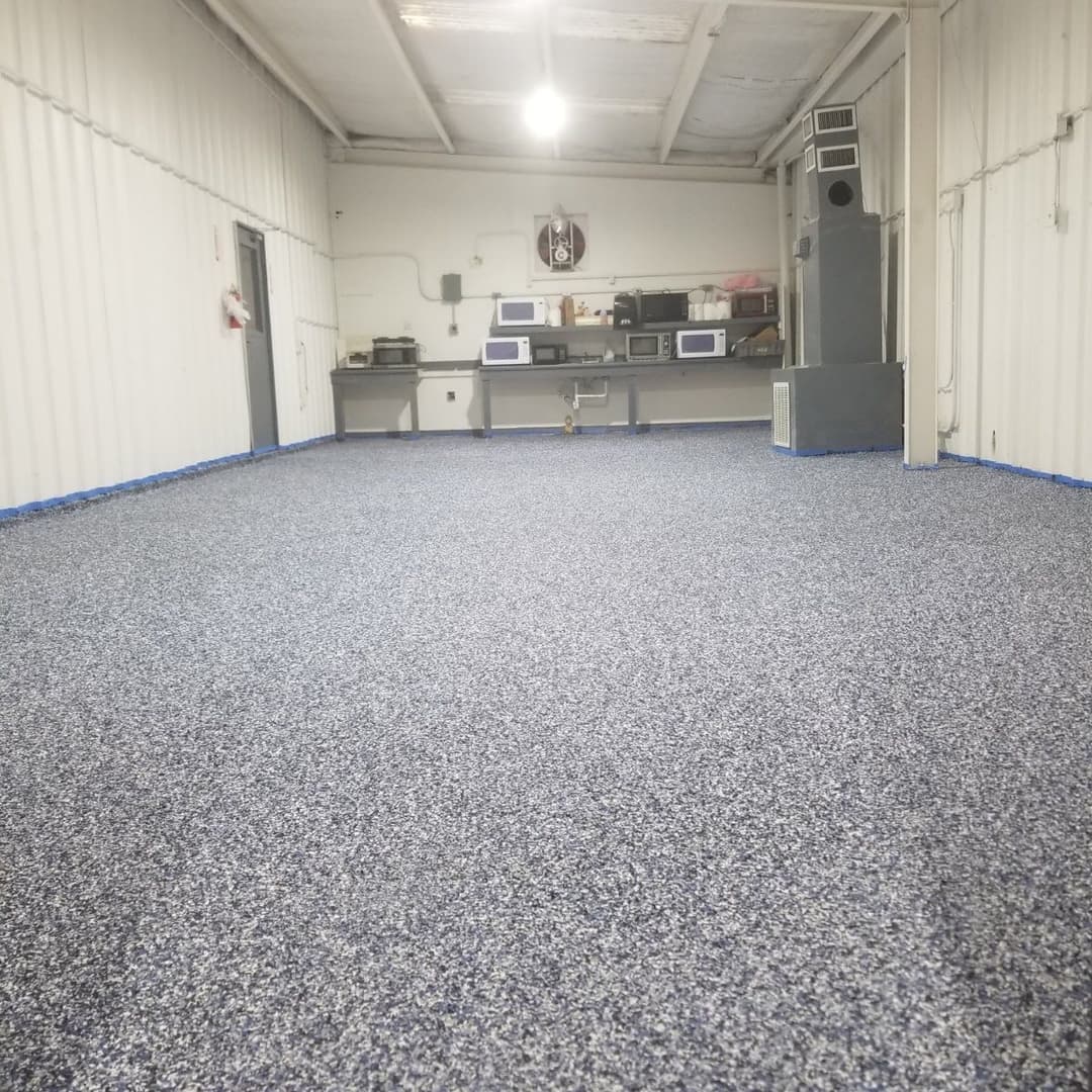Newly installed textured flooring in industrial space with appliances in background.