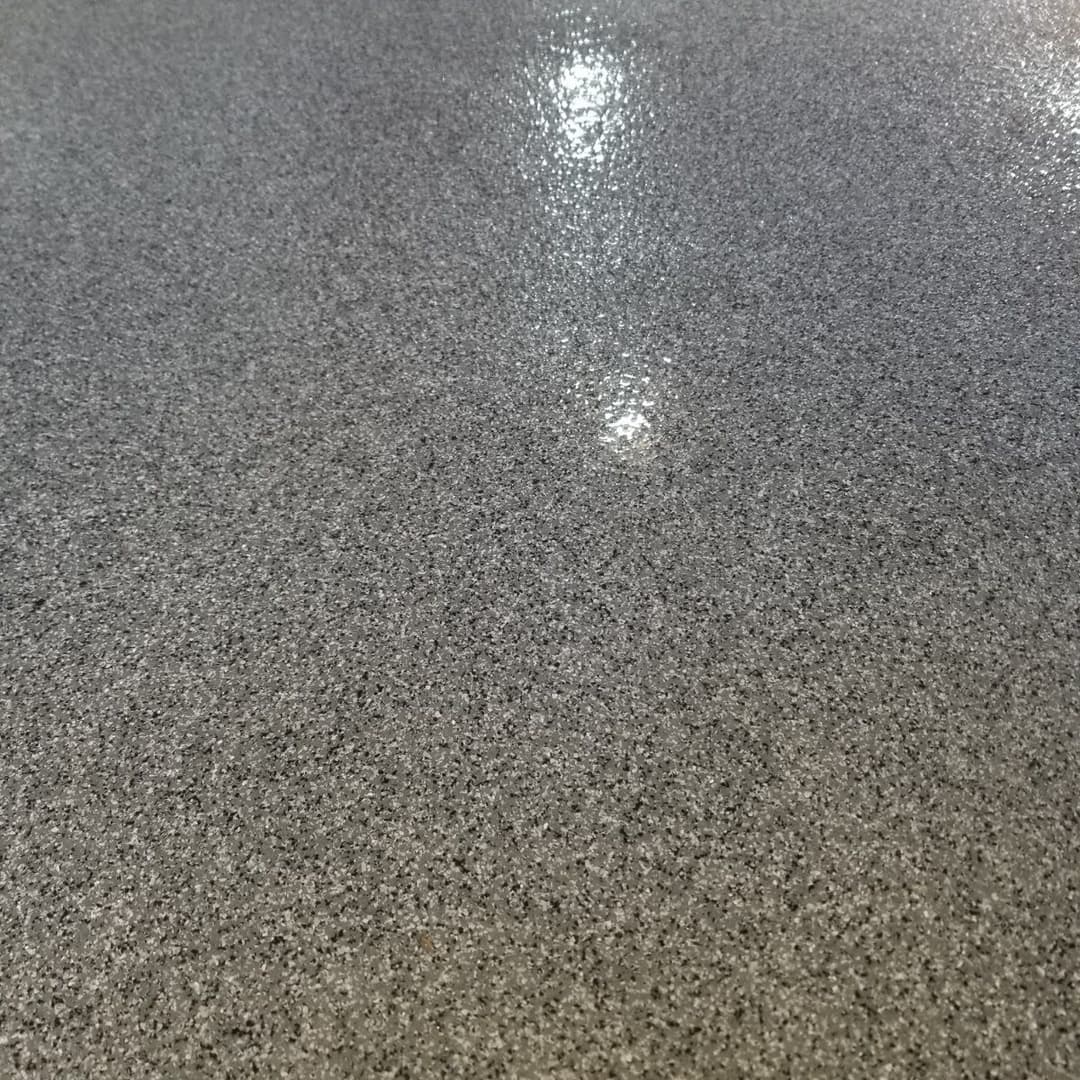 Glossy gray epoxy flooring texture with reflective surface and subtle speckles.