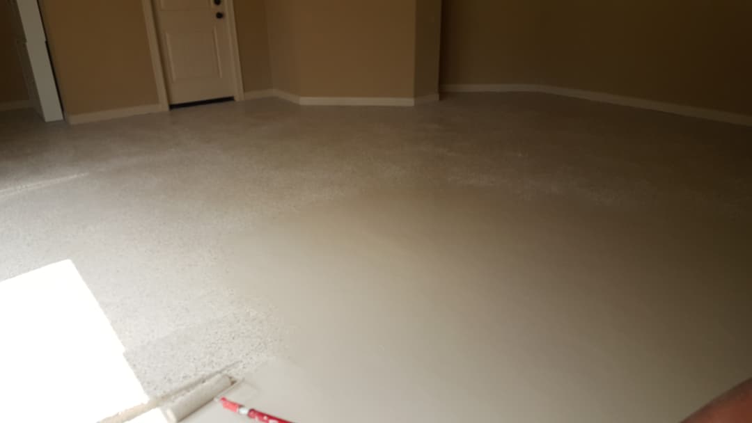 Freshly applied smooth epoxy floor in a light-colored room with beige walls.