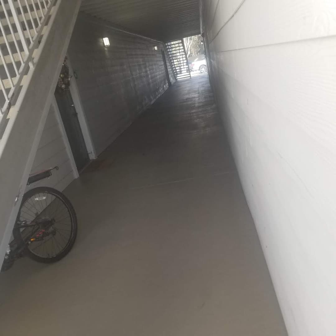 Long hallway with a bicycle parked on the side and light illuminating the pathway.