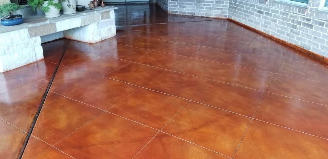 Polished, stained concrete patio with rich brown tones and decorative planters.