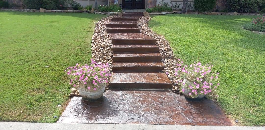 Pathway with stone steps, bordered by flowers and landscaping, leading to a front door.