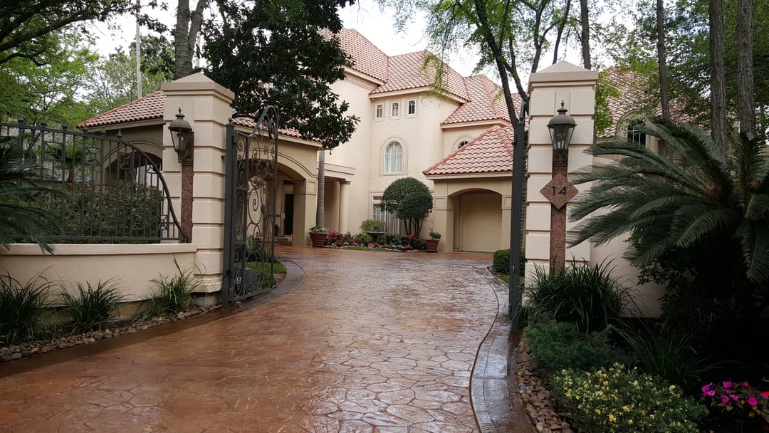Elegant two-story home with a textured driveway, landscaped gardens, and ornate entrance.