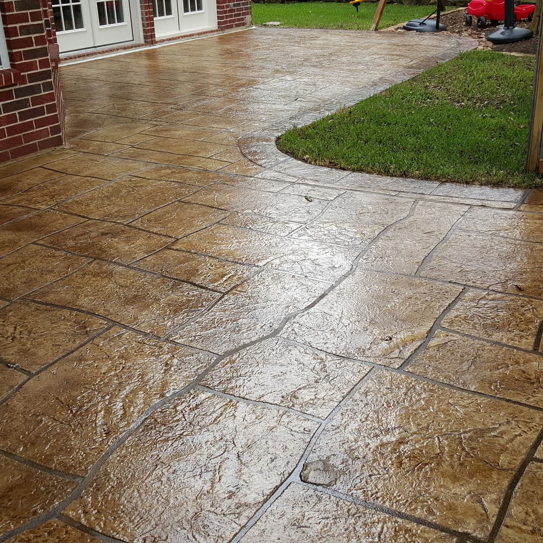 Stylish stamped concrete patio with a glossy finish and lush green lawn.