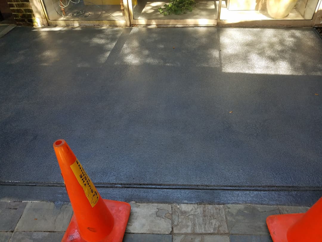 Freshly poured concrete surface with orange traffic cones marking the area.