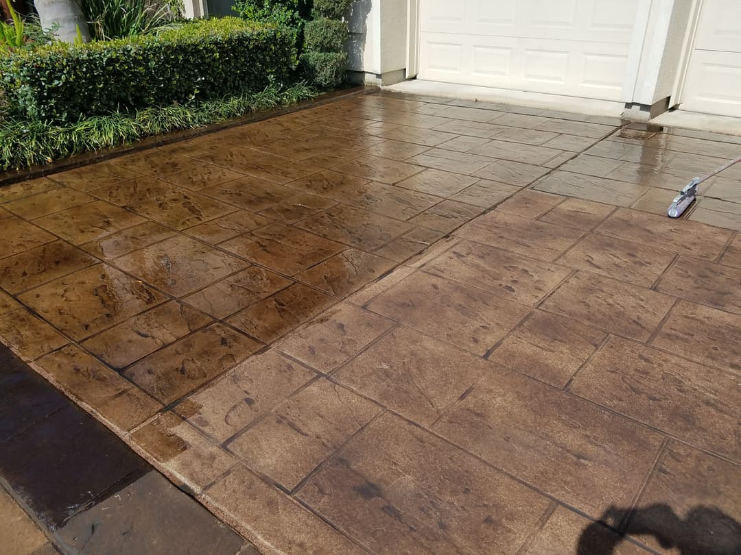 Cleaned stamped concrete driveway, showcasing before and after sections with clear distinctions.