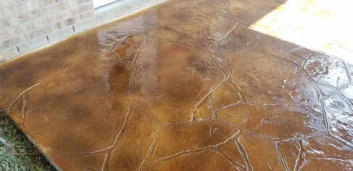 Decorative stained concrete patio with a textured stone pattern and earthy tones.