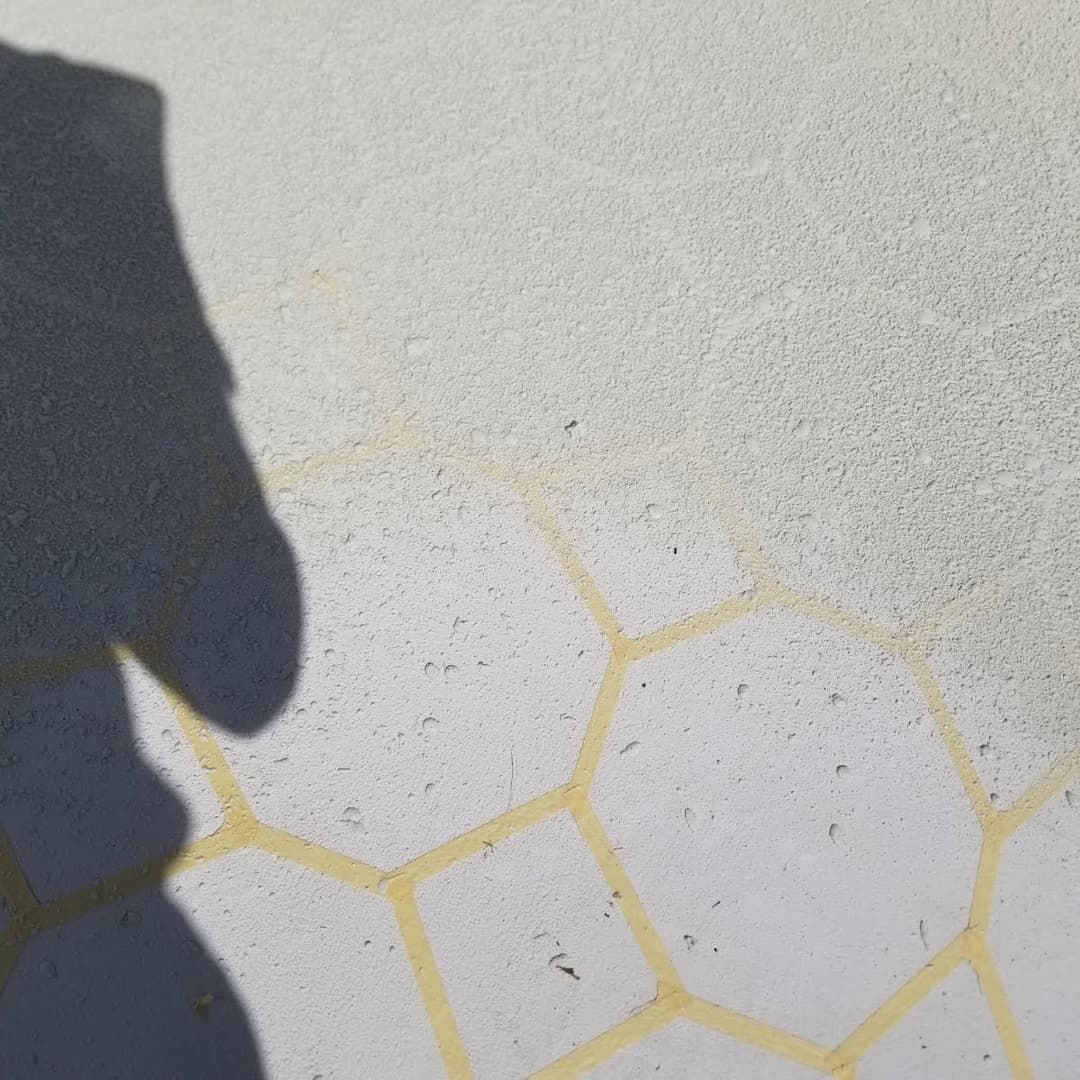 Honeycomb-patterned concrete surface with a shadow casting over it.