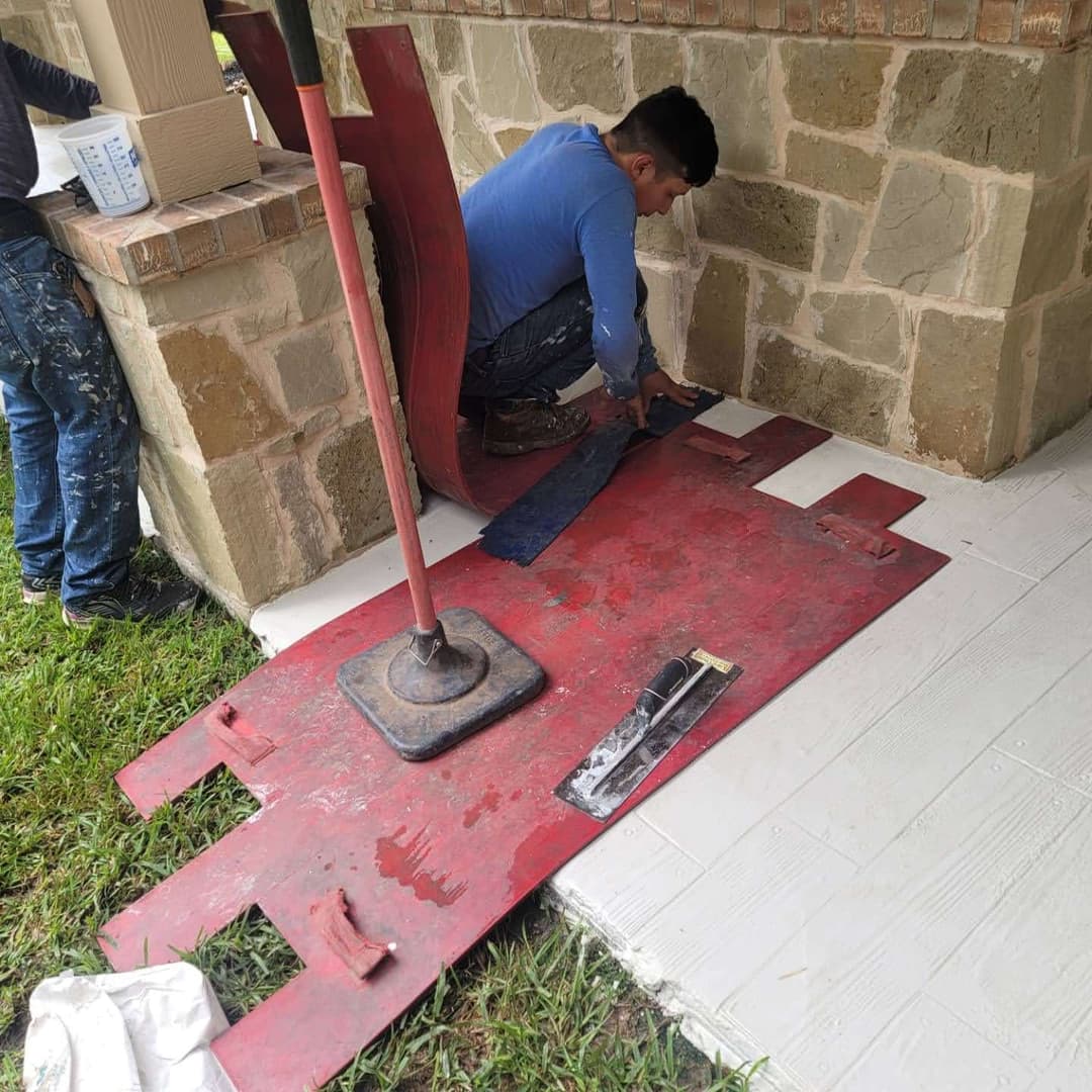 Worker installing flooring on a porch with tools and materials nearby.