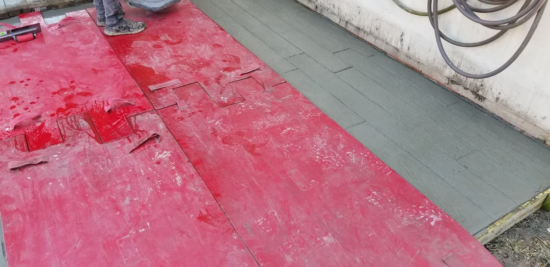 Laborer installing red and green interlocking floor tiles at a construction site.