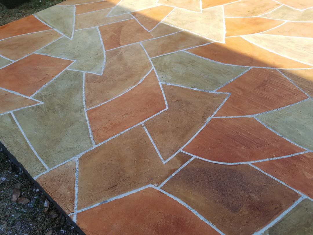 Colorful patterned concrete patio with orange and beige mosaic design.