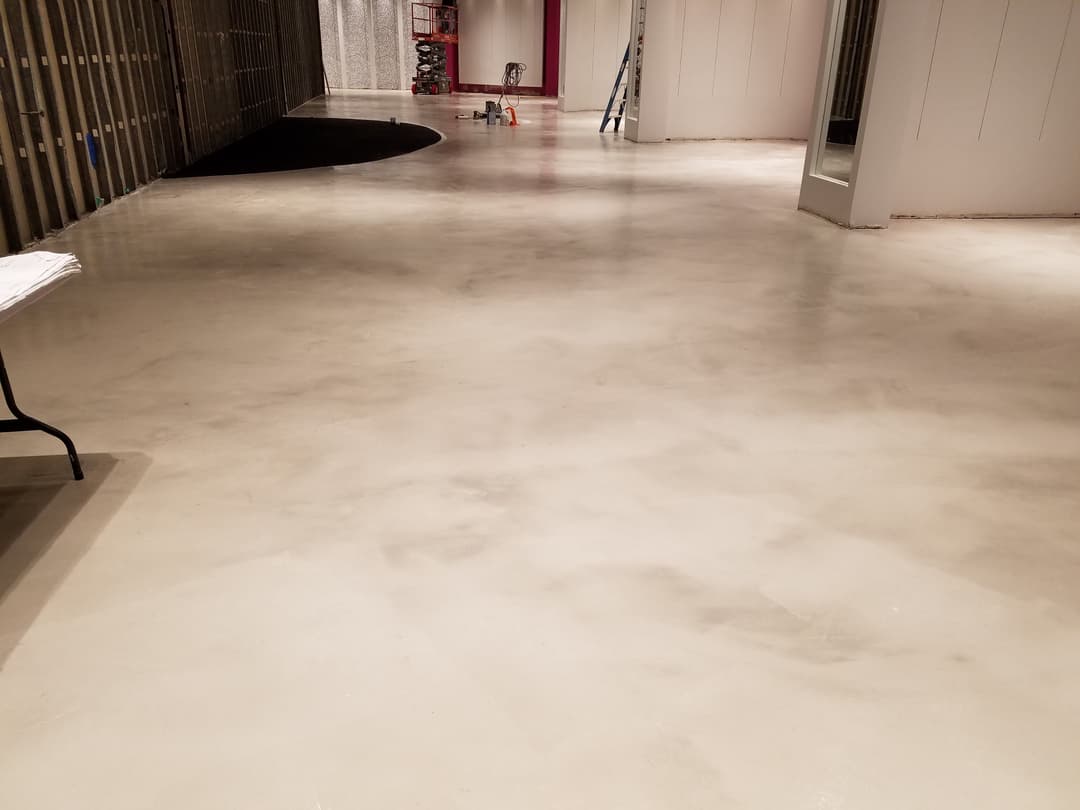 Polished concrete floor in a spacious interior under construction with tools and materials nearby.