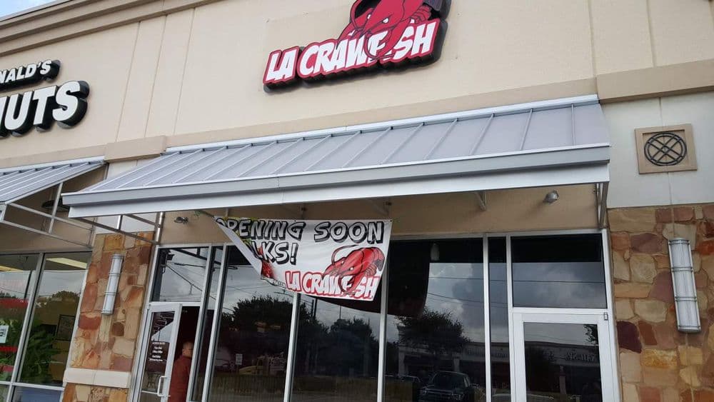 Sign for La Crustacean seafood restaurant, "Opening Soon", outside a retail storefront.