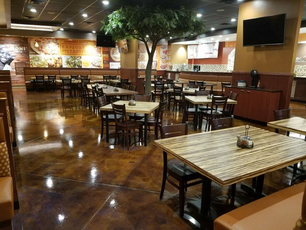 Spacious restaurant interior with wooden tables, chairs, and a decorative tree.