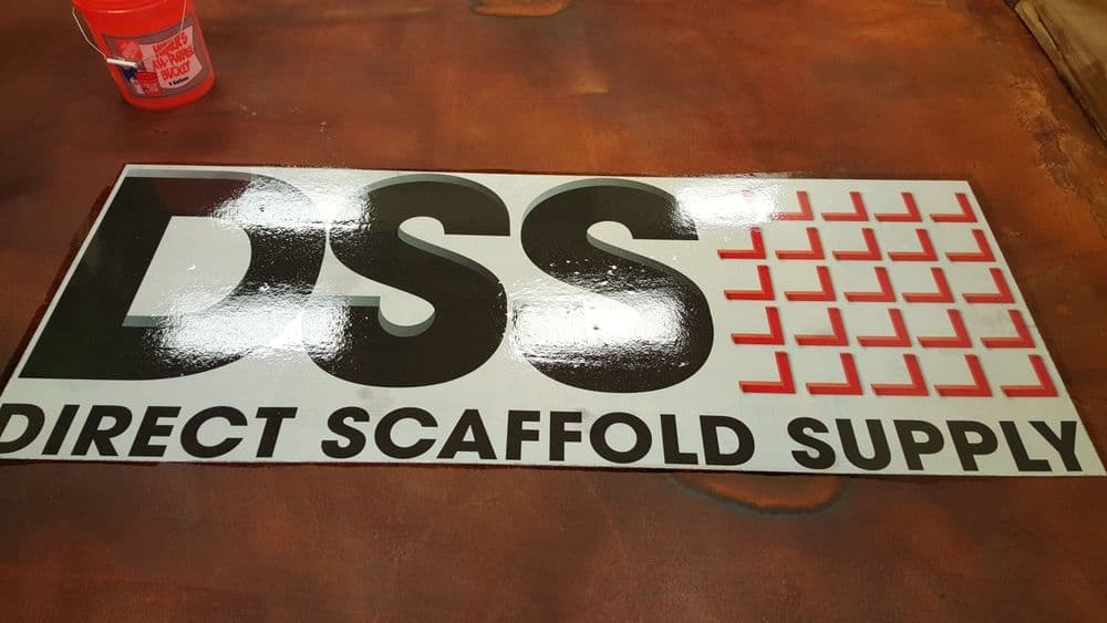 Direct Scaffold Supply logo on a sign, featuring bold letters and a red grid design.